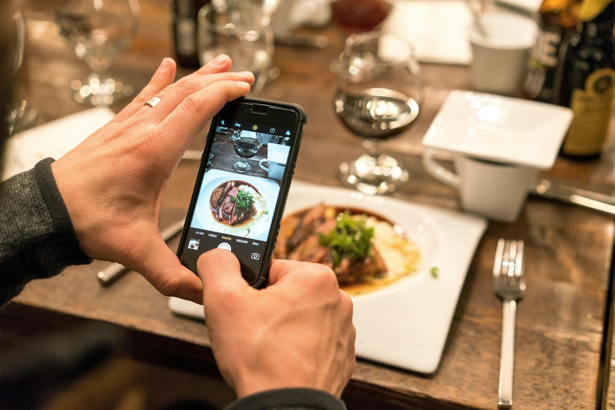 A person photographing a meal with a smartphone.
